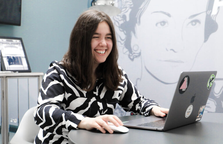 Madeline smiling in front of her laptop