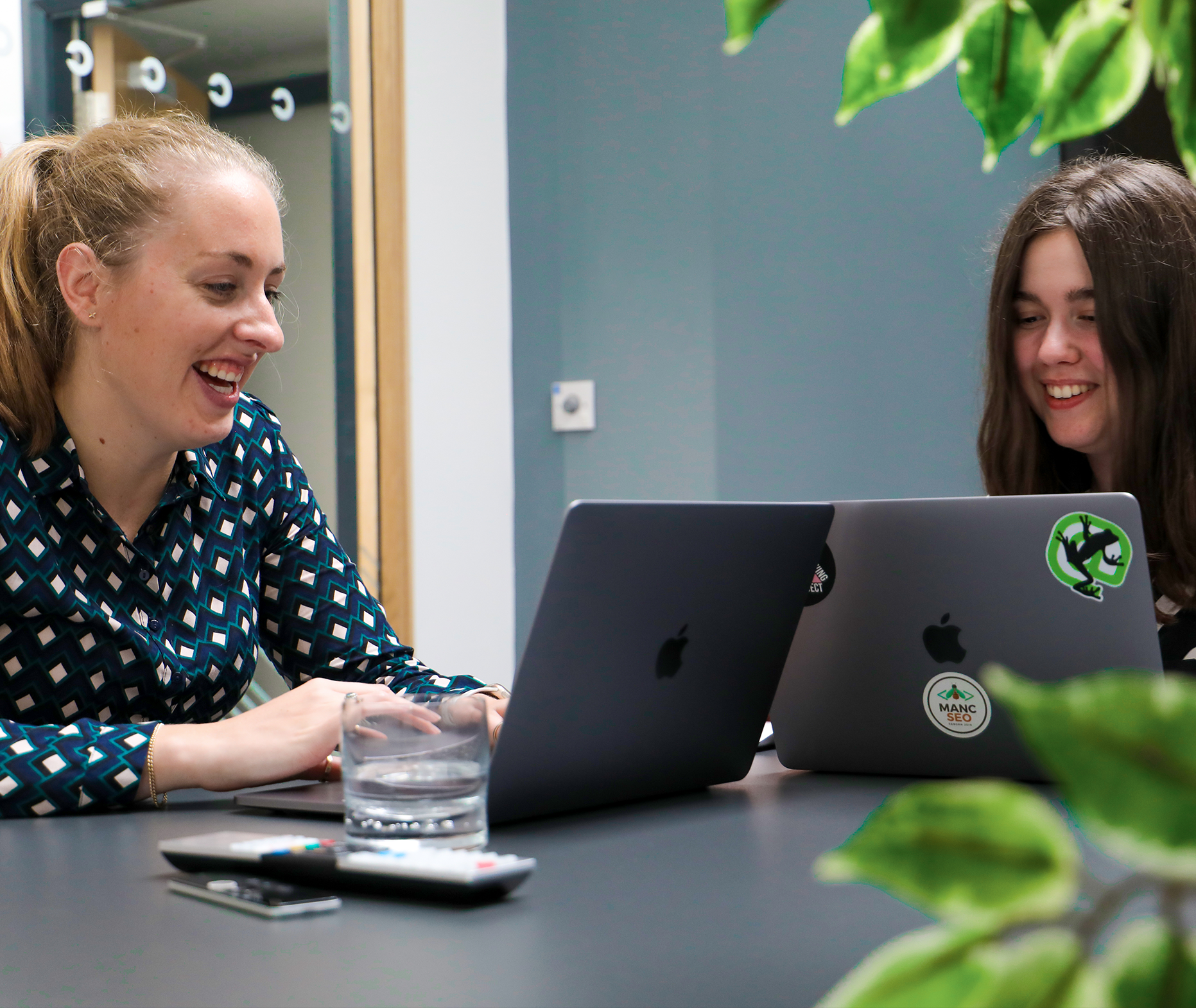 Two team members at cornerstone - Account Manager Rhiannon Pearce and Junior Digital Marketer Maddy Thorp using their laptops in a meeting