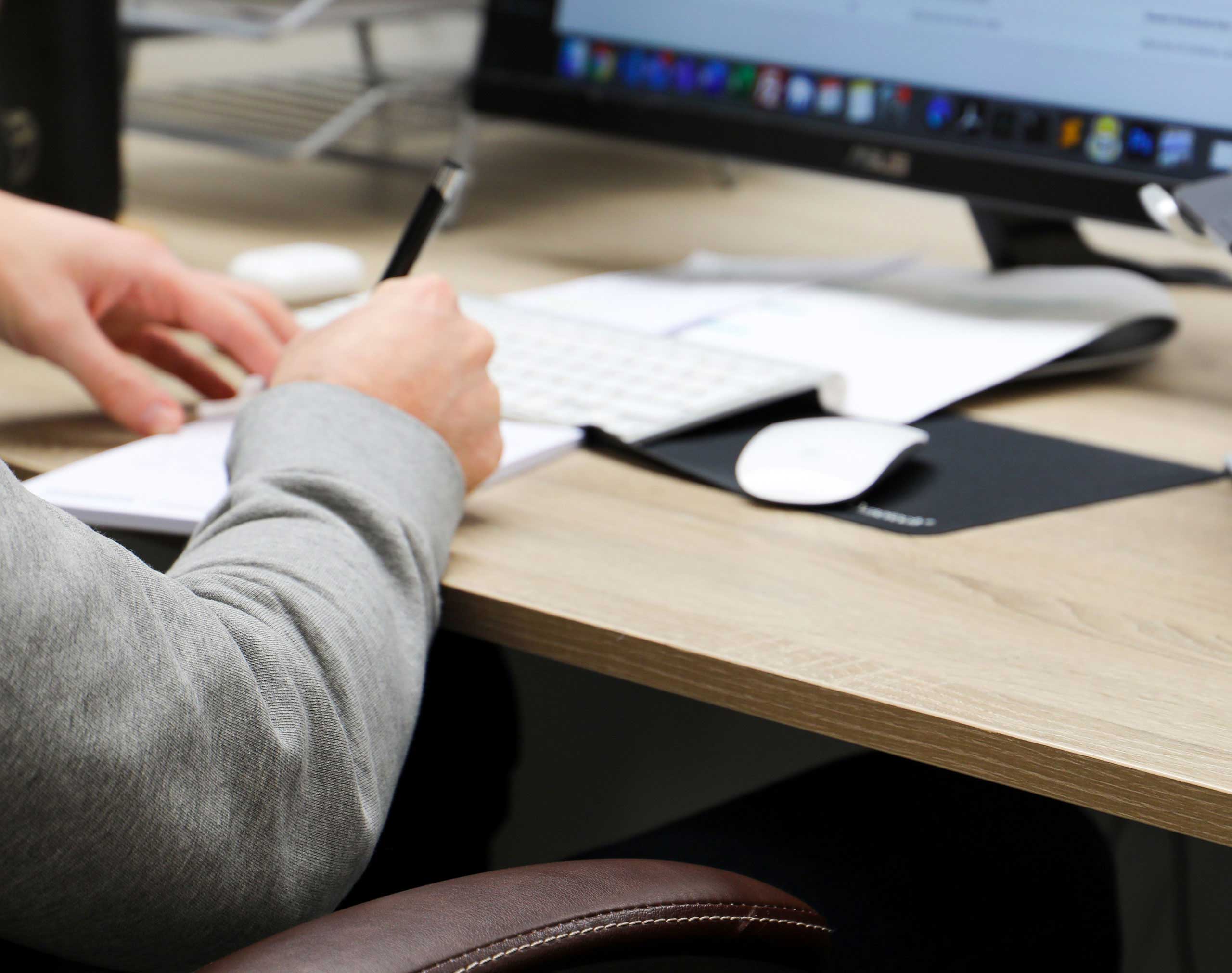 Close up of person sat at a desk writing notes