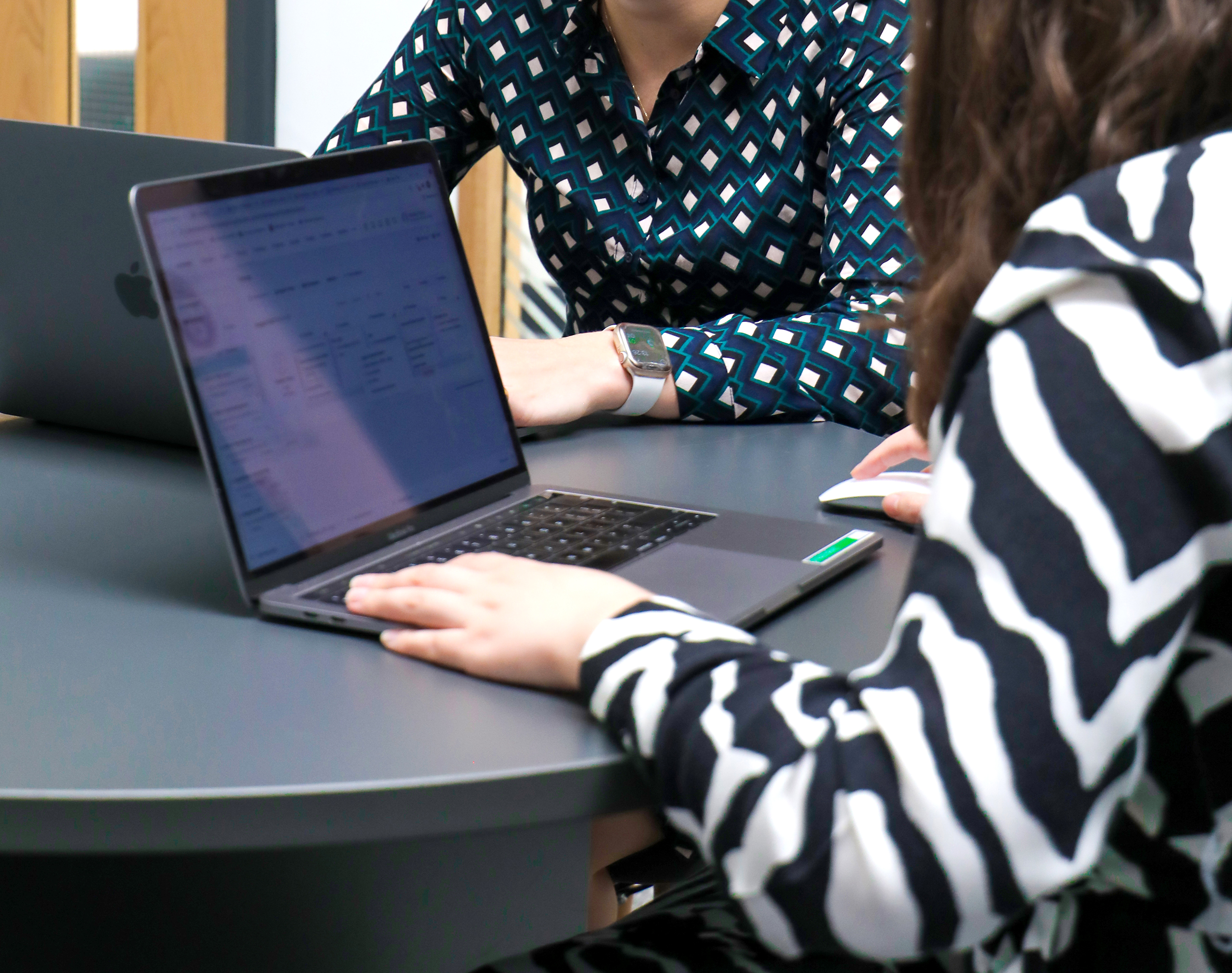 Two female team members from Cornerstone in a meeting with laptops